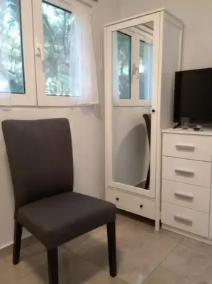 a chair in a room with a dresser and a television at Astrinos Apartment Simple cozy comfortable close to the beach in Chania Town