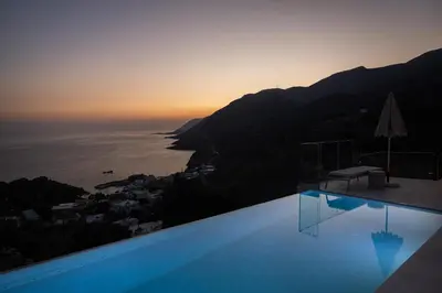 a pool with a view of the ocean at sunset at Villa Dóma in Sfakiá