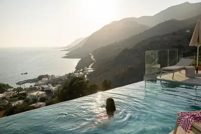 a person in a infinity pool with a view of the ocean at Villa Dóma in Sfakiá