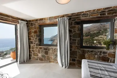 a room with a stone wall and two windows at Villa Dóma in Sfakiá