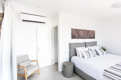 a white bedroom with a bed and a chair at Villa Dóma in Sfakiá