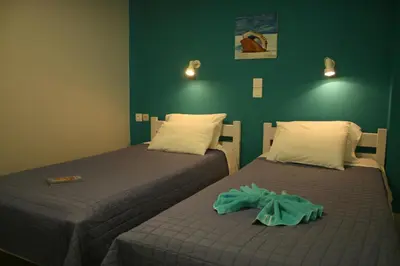 two beds in a room with green walls at Nereides Hotel in Kolymvari