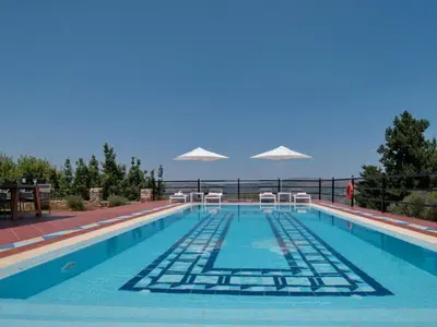 a swimming pool with chairs and umbrellas at Villa Artemis Vryses Crete in Alikampos