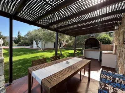 a wooden table and chairs under a pergola at Villa Artemis Vryses Crete in Alikampos
