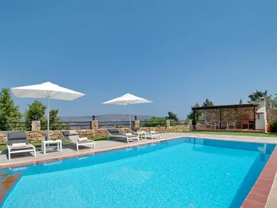 a swimming pool with two chairs and umbrellas at Villa Avra Vrisses Crete in Alikampos