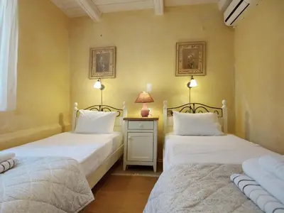 a bedroom with two beds and a table with a lamp at Villa Vigla in Samonás