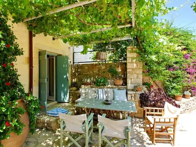 a patio with a table and chairs under a pergola at Villa Vigla in Samonás