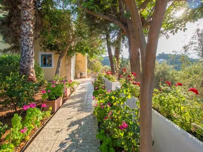 a garden with flowers and trees and a sidewalk at Villa Clio with Pool Stalos Crete in Stalos