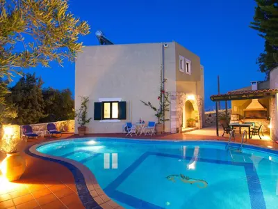 a villa with a swimming pool at night at Villa Panos in Stalos in Stalos