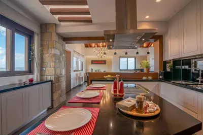 a kitchen with white cabinets and a black counter top at VenMar luxury house in Plataniás