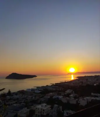 a sunset over the ocean and a city at VenMar luxury house in Plataniás