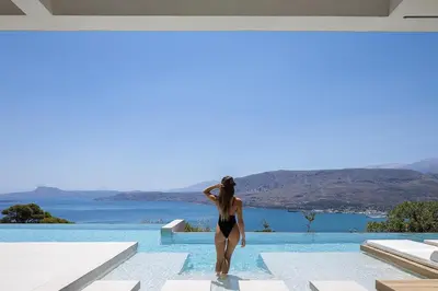 a woman in a black bikini standing on the edge of a swimming pool at Avery Villa in Chania Town
