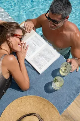 a man and woman reading a book next to a pool at Avery Villa in Chania Town