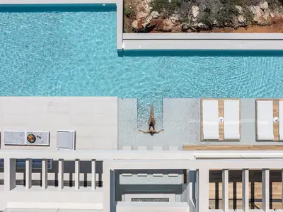 a person on a surfboard in the water next to a pool at Avery Villa in Chania Town