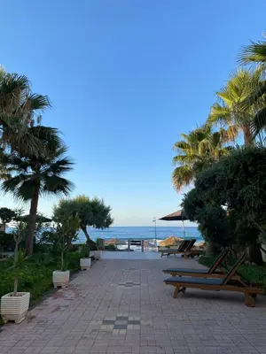 a walkway with benches and palm trees and the ocean at Be Crete - Zen Appartments 1 room in Agia Marina Nea Kydonias