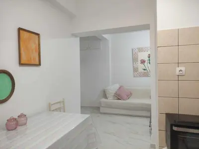 a white living room with a couch and a table at Teos App in Chania Town
