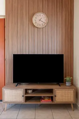 a flat screen tv on a wall with a clock at Armeria Apartments I I in Daratso