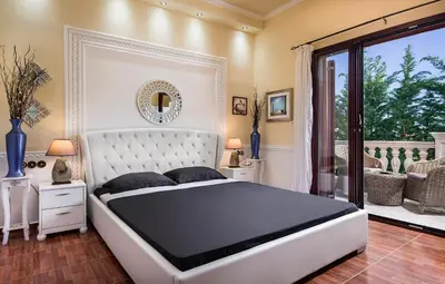 a bedroom with a large white bed and a balcony at Pandis Palace in Agios Onoufrios