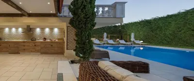 a pool with chairs and a table and a house at Pandis Palace in Agios Onoufrios