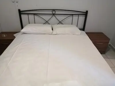 a bed with a black frame and white sheets and pillows at Ελευθέριος, rooms 1 in Chania Town