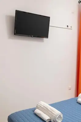 a room with a bed with a flat screen tv on the wall at Orange Seaside Apartment in Galatás