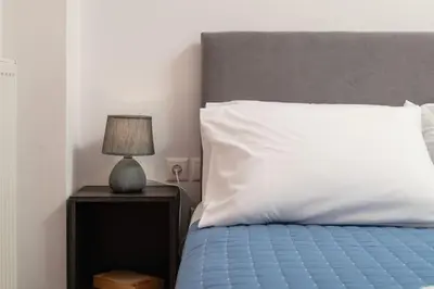 a bed with a white pillow and a lamp on a night stand at Orange Seaside Apartment in Galatás
