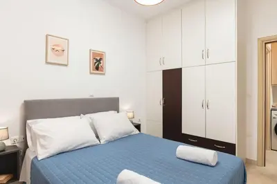 a bedroom with a blue bed with white cabinets at Orange Seaside Apartment in Galatás