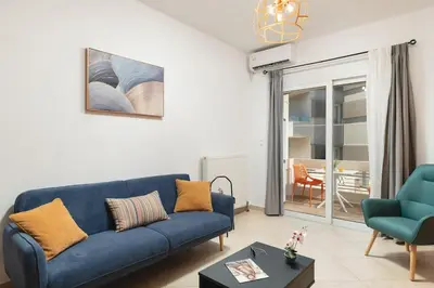 a living room with a blue couch and a table at Orange Seaside Apartment in Galatás