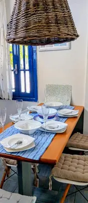 a table with plates and wine glasses and a chandelier at Erofili Apartment in Kalyves
