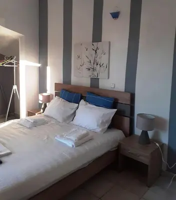 a bedroom with a large white bed with blue accents at Erofili Apartment in Kalyves