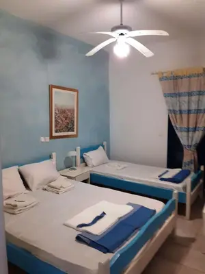 two beds in a room with a ceiling fan at Erofili Apartment in Kalyves