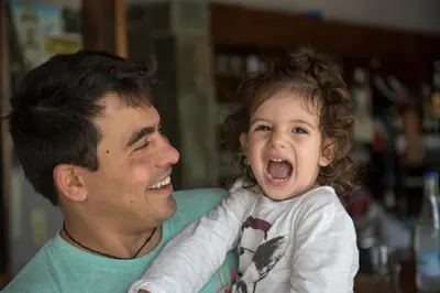a man holding a little girl with her mouth open at Proimos Apartments in Gerani Chanion