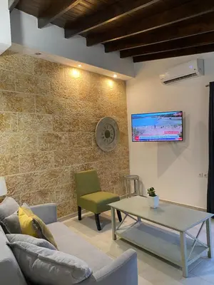 a living room with a couch and a table and a tv at Be Crete - Zen apartment 2 rooms in Ayiá