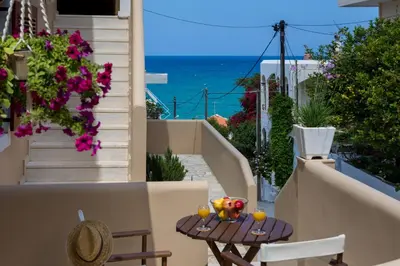 a balcony with a table and chairs and the ocean at Avra Apartments in Kalyves