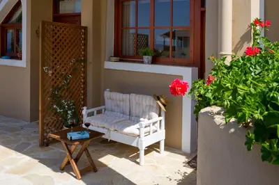 a porch with a white chair and a table and flowers at Avra Apartments in Kalyves