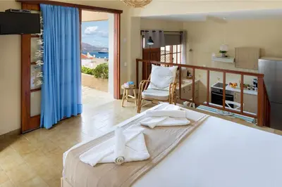 a bedroom with a bed and a kitchen with a balcony at Avra Apartments in Kalyves