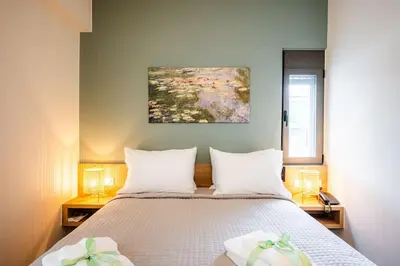 a bedroom with a bed with white sheets and two lamps at Erato - Newly renovated Home with Parking in Chania Town