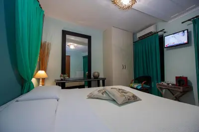 a bedroom with a white bed with green curtains at Elia Portou Rooms in Chania Town