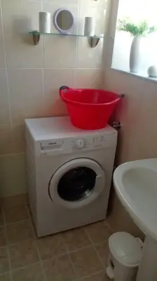 a washing machine with a red bucket on top of it at QUIET NEW Apartment-5' to the beach, 15' to center in Chania Town