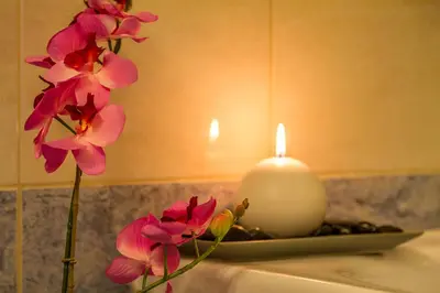 a candle and pink flowers on a bathroom sink at Cyan Icons Villas Kalyves Chania in Kalyves
