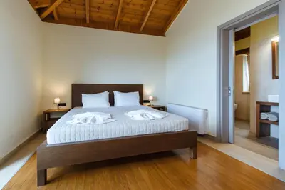 a bedroom with a bed with white sheets and wooden floors at Villa Kalithea in Kissamos