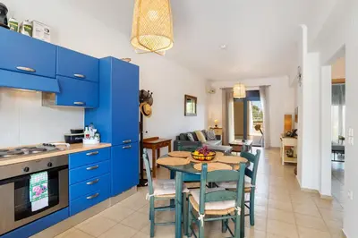 a kitchen and living room with blue cabinets and a table at Almyrida Bay View House III BY APOKORONAS-VILLAS in Almirida