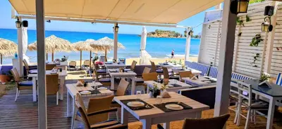 a restaurant on the beach with tables and chairs at Sky & Sea 3 in Kato Daratso