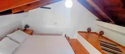 a small bedroom with a bed and a wooden staircase at Sky & Sea 3 in Kato Daratso