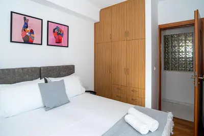a bedroom with a white bed and a wooden cabinet at CityNest apartment in Chania Town