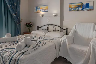 a bedroom with a bed with a chair and towels at Alena Apartments in Chania Town