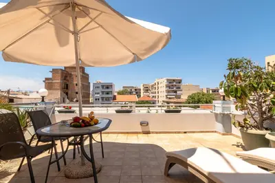 a patio with an umbrella and a table with fruit at Alena Apartments in Chania Town