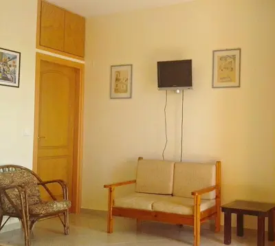 a living room with a couch and a tv on the wall at Kleio Studios in Ravdhoúkha