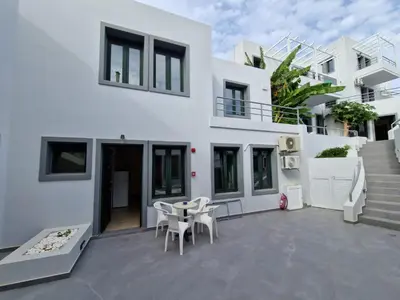 a white house with a patio with a table and chairs at Rainbow Hotel Apartments in Chania Town