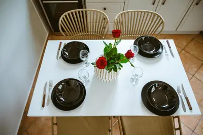 a white table with plates and red roses on it at Elafonisi - Cretan Serenity - Private Pool in Elafonisi